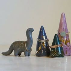 three small toy dinosaurs are standing next to each other on the table, one is wearing a ring