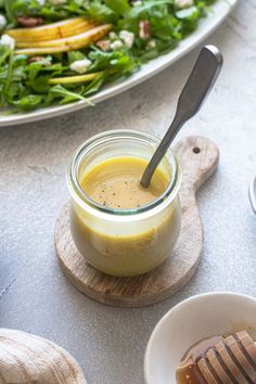 a salad with dressing in a glass jar on a wooden board next to a plate