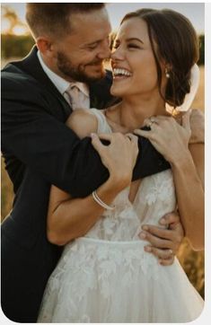 a bride and groom embracing each other in a field