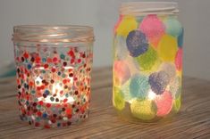 there are two jars that have different colored dots on them and one has a lit candle in it