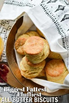 a wooden bowl filled with biscuits next to an orange slice and some jam on the side