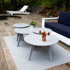 two white tables sitting on top of a wooden floor next to a blue couch and chair