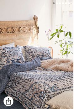 a bed with blue and white bedspread next to a plant in a window