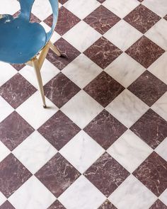 a blue chair sitting on top of a checkered floor next to a metal table