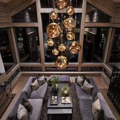 a living room filled with lots of couches and lamps hanging from the ceiling next to windows