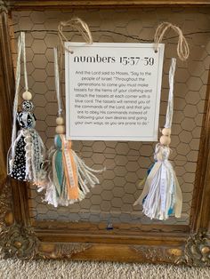 three tassels hanging from a frame with a sign on the wall behind them