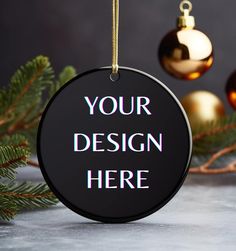 a black round ornament hanging from a christmas tree with ornaments around it that says your design here