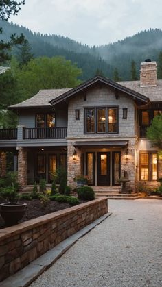 a large house in the middle of a wooded area with trees and mountains behind it