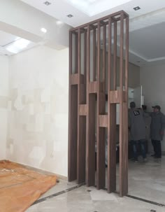 two men standing in an unfinished room with wooden partitions