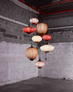 a bunch of lights hanging from the ceiling in a room with brick walls and concrete flooring