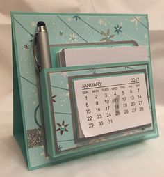 a desk calendar with a pen on top of it and a pocket for notes to write