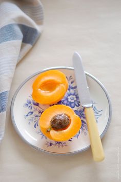 two peeled apricots on a plate with a knife