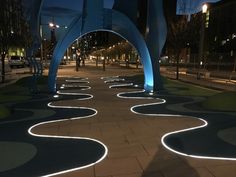 an illuminated walkway in the middle of a city at night