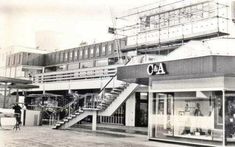 an old black and white photo of people walking in front of a building with stairs