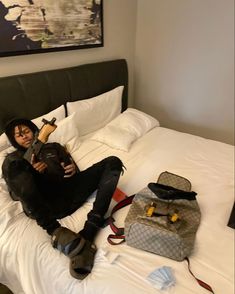 a woman laying on top of a bed next to a bag and purse with her legs crossed