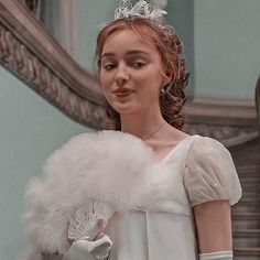 a woman in a white dress and tiara standing next to a mirror with her hands on her hips