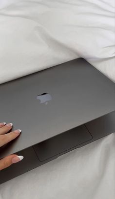 a woman's hand holding onto an apple laptop