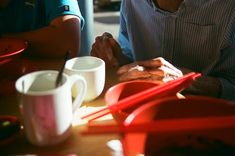 two people sitting at a table with plates and cups on it, one person is holding the other's hand