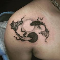 a black and white tattoo on the back of a woman's shoulder