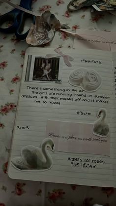 an open notebook with swans on it and some scissors next to the pages that have been altered