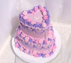 a three tiered cake with pink and purple frosting roses on the bottom layer