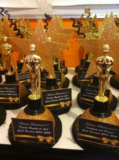 many awards are lined up on a table with gold and black trophies in front of them