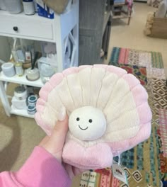 a person holding a stuffed animal with a smile on it's face in their hand