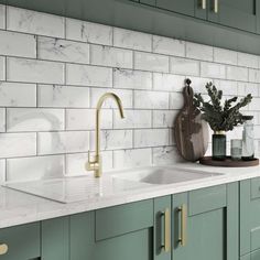 a kitchen with green cabinets and white marble counter tops, gold faucets and brass handles