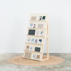 a book shelf with pictures on it in front of a white wall and round rug