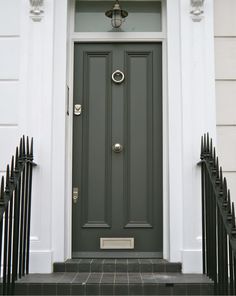 the front door of a house with black wrought iron railings and a green door