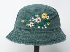 a green hat with white and yellow flowers embroidered on it's brimming