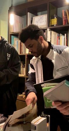 two men are looking through mail in an office area with bookshelves and shelves