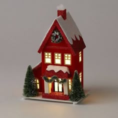 a red house with christmas decorations on the roof and windows is lit up at night