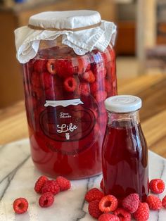 raspberry jam in a glass jar next to fresh raspberries