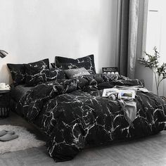 a black and white marbled comforter set on a bed in front of a window