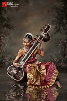 a woman sitting in the water holding an instrument