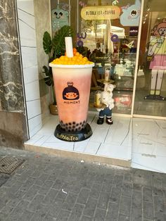 a tall cup filled with oranges sitting on top of a sidewalk next to a store front