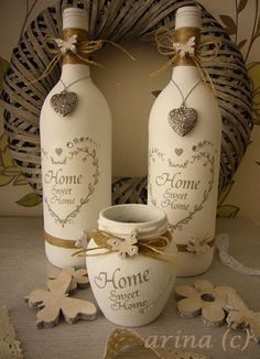 two white bottles with hearts on them sitting next to a vase and doily in front of a wreath