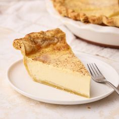 a piece of pie on a plate with a fork next to it and another pie in the background