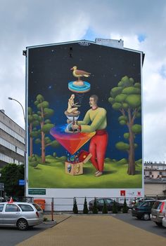 a large mural on the side of a building with a man holding a bird and a dog