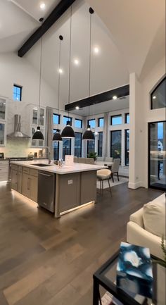 a large open concept kitchen and living room with wood flooring, high ceiling lighting, and white walls