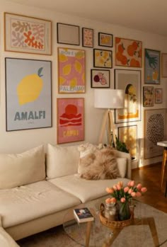 a living room filled with white furniture and pictures on the wall above it's coffee table