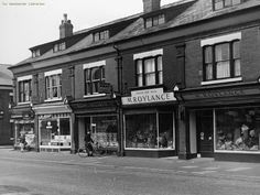 an old black and white photo of people walking down the street in front of stores