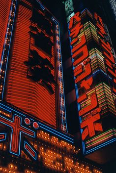 a tall building with neon lights on it's sides and the words tokyo written in japanese