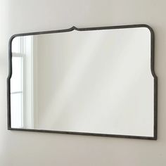 a large mirror hanging on the wall above a sink in a room with white walls