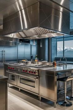 an industrial kitchen with stainless steel appliances and large windows looking out on the mountain range