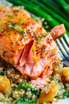 salmon and quinoa on a white plate with a fork next to asparagus