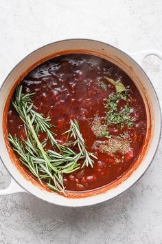 a pot filled with soup and herbs on top of a table