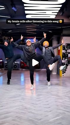 three people are dancing in a dance studio with their hands up and one person is wearing black