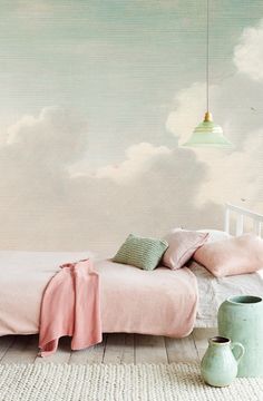 a bed with pink sheets and pillows in front of a cloudy sky wallpaper mural